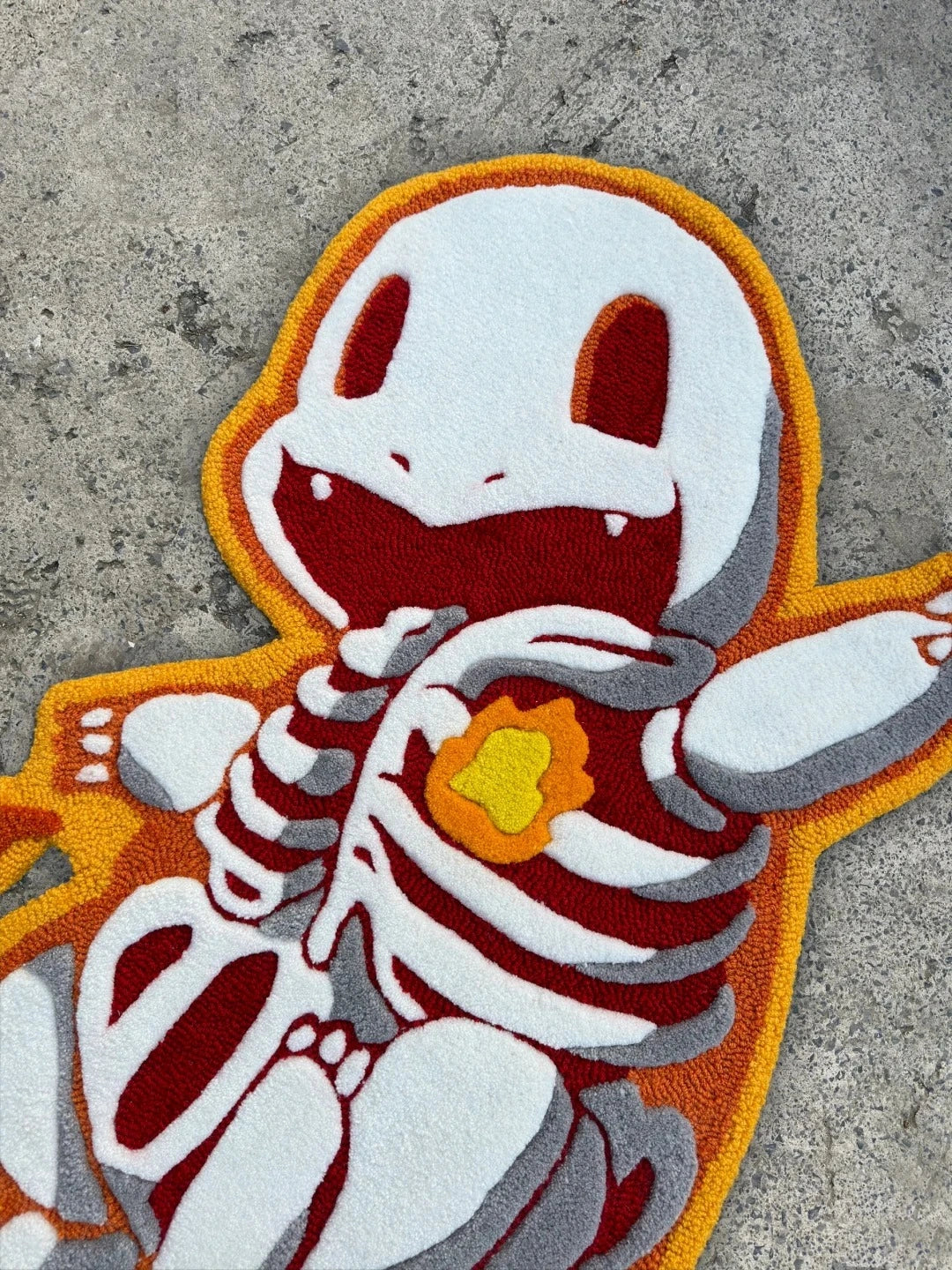 Close-up detail of the flame-heart lizard tufted rug highlighting the textured pile, stitch precision, and the heart-flame motif within the reptile design.