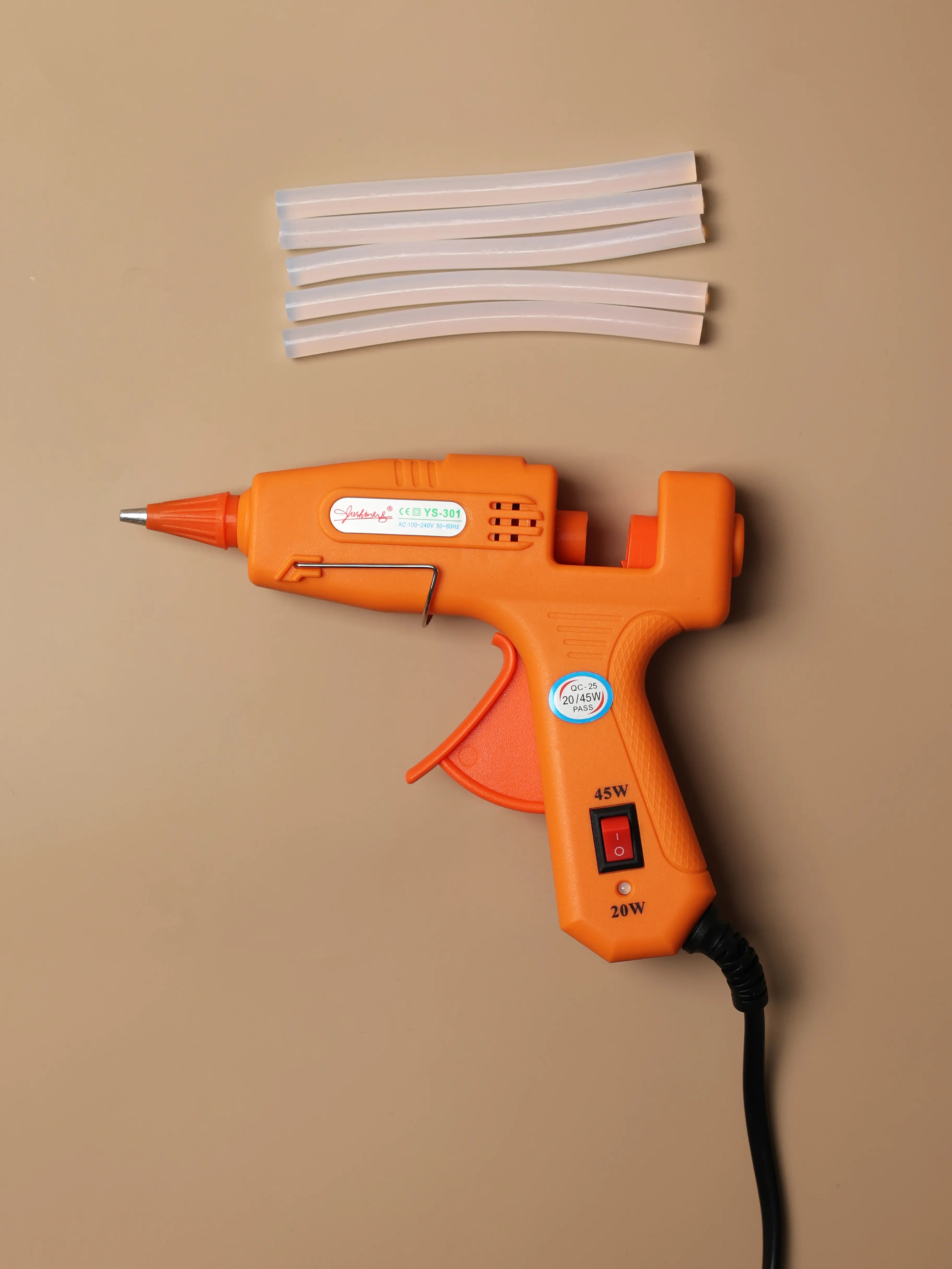 Mini hot glue gun paired with clear glue sticks, showing the full set used for sealing tufted rugs and general craft bonding.