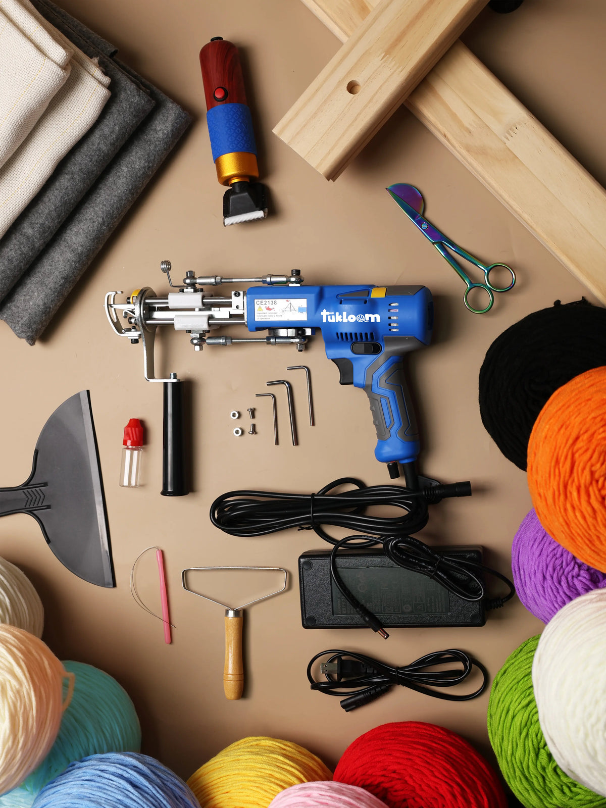 Complete AK-V tufting kit with gun, frame, dual backing fabrics, electric trimmer, scissors, and yarn cones for professional rug studios