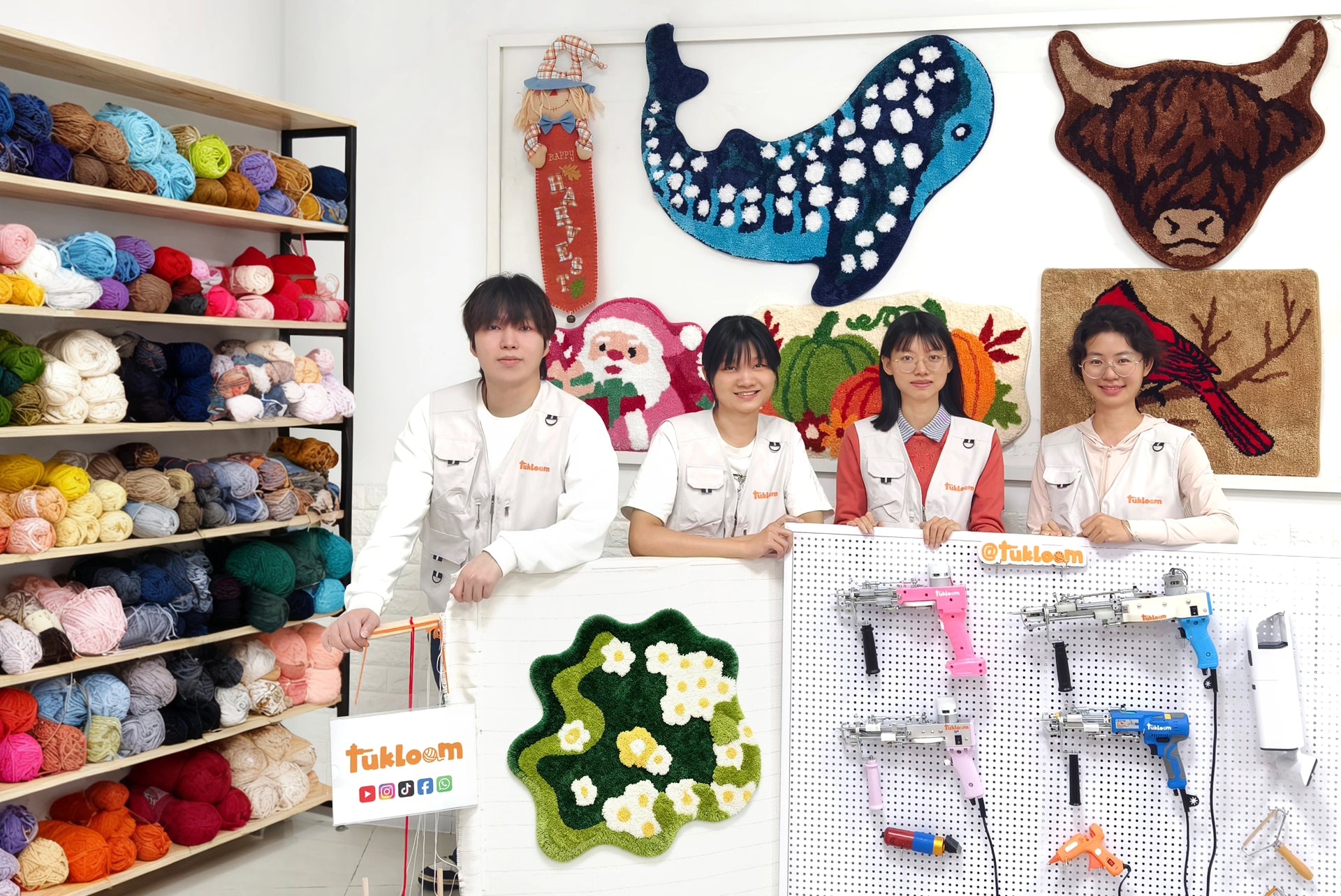 The Tukloom team posing in front of tufted rugs and tufting guns, showcasing handmade rug art and creative tools.